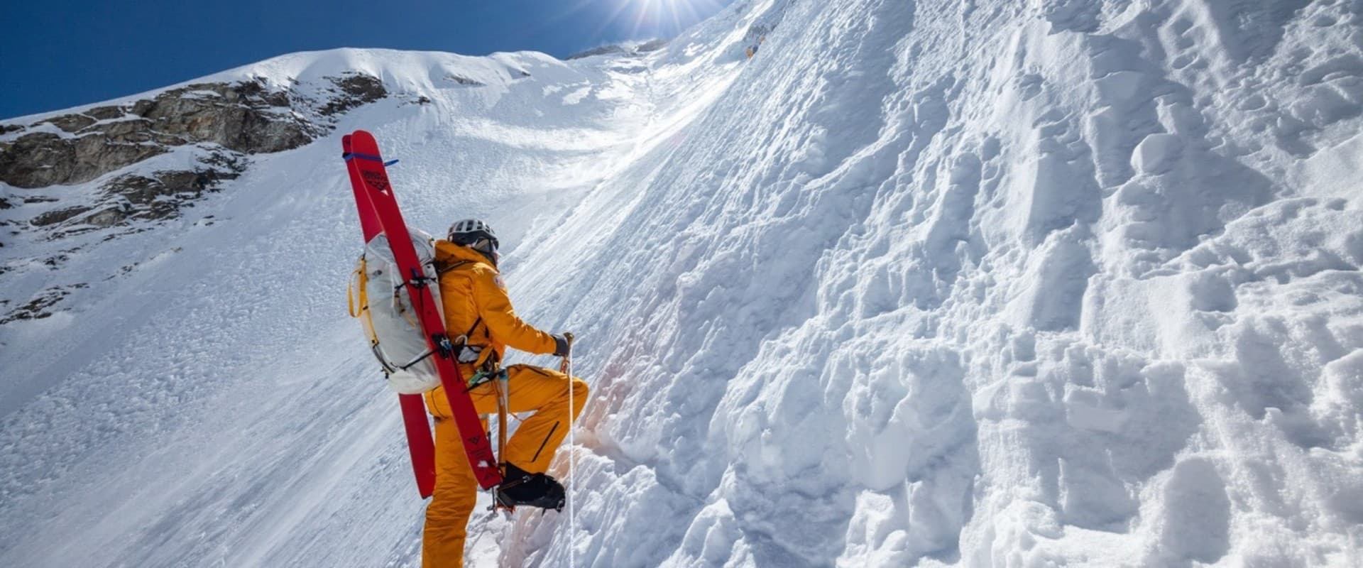 Jim Morrison ascends a sheer wall of ice and snow with a pair of skis strapped to his back in 'Everest: The Other Side' (2026).