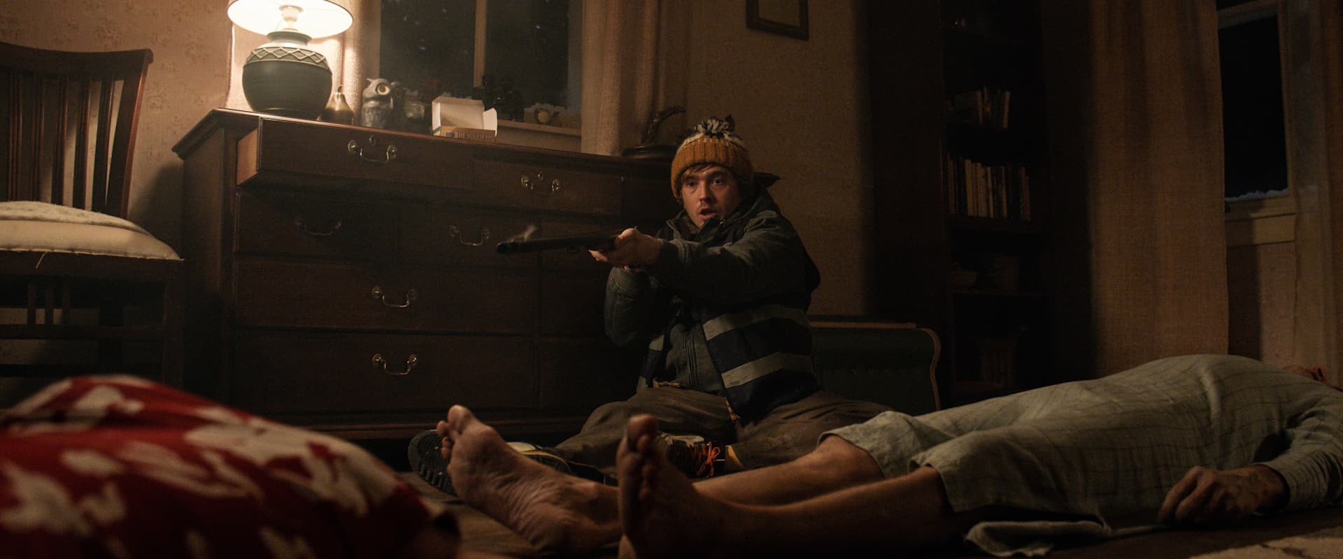 A courier (Austin Abrams) sits in shock on the floor, a smoking shotgun clutched in his hands in 'Resident Evil' (2026).